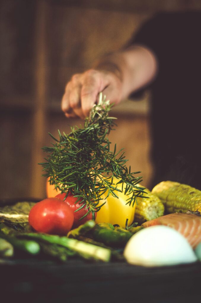 pexels-photo-1566867-1566867 A vibrant assortment of fresh vegetables and herbs, including tomatoes and rosemary, being prepared for grilling.